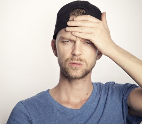 man holding hand to his head to feel temperature